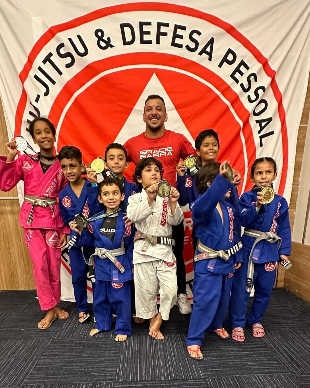 Turma infantil da GB Pendotiba exibindo medalhas com o professor