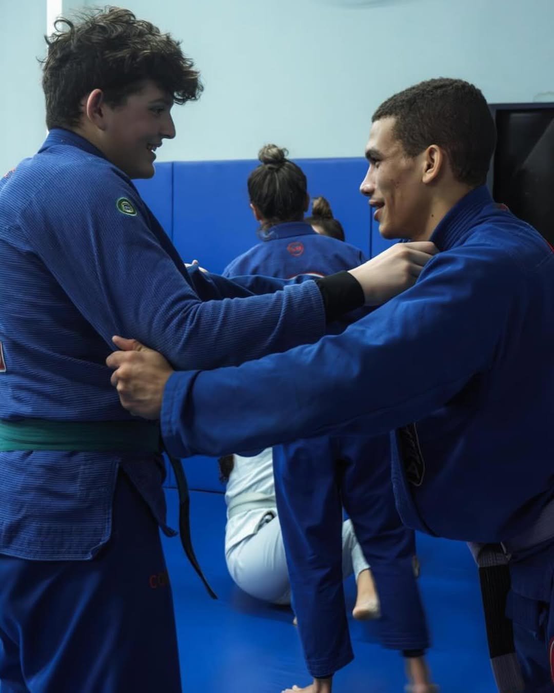 Alunos juvenis treinando Jiu-Jitsu de kimono azul no tatame